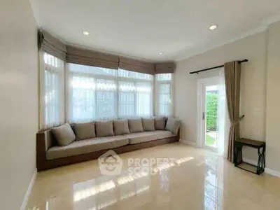 Spacious living room with large windows and elegant curtains, featuring a cozy corner sofa and polished floors.