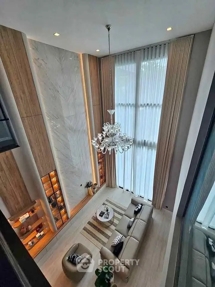 Luxurious high-ceiling living room with elegant chandelier and floor-to-ceiling windows