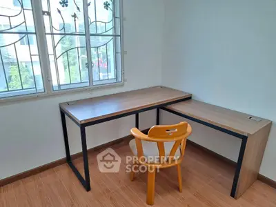 Bright study room with modern desk and chair, featuring large window and wooden flooring.