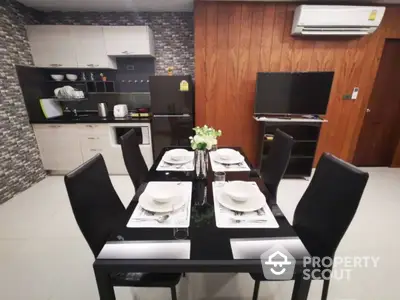 Modern dining area seamlessly integrated with a stylish kitchen, featuring sleek black dining furniture, stone accent wall, and wood paneling.