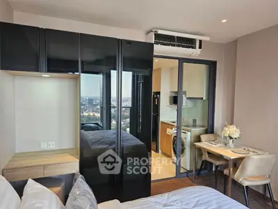 Modern studio apartment with glass wardrobe and city view, featuring a compact kitchen and dining area.