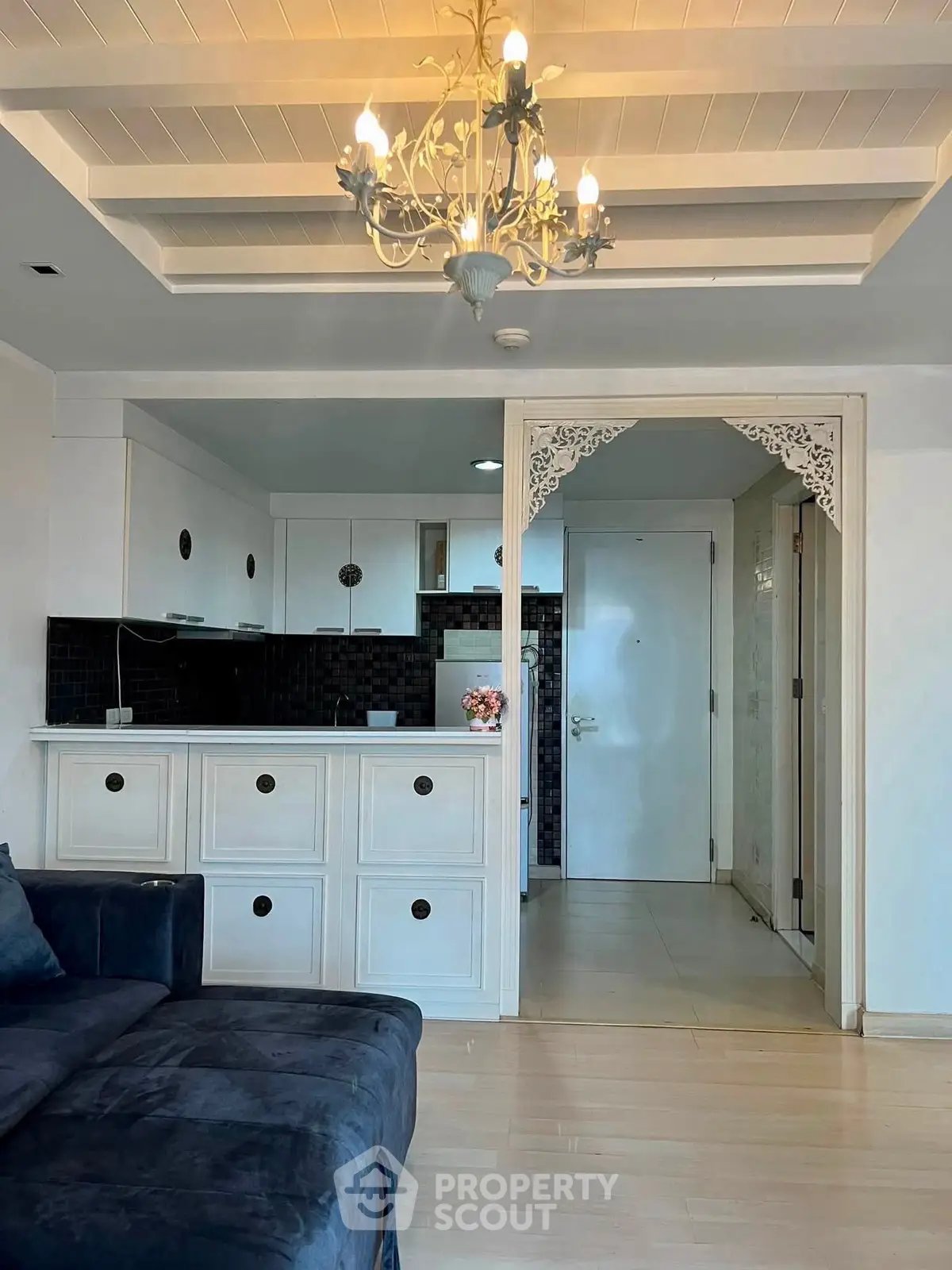 Charming open-layout living room with elegant chandelier and modern kitchen design.