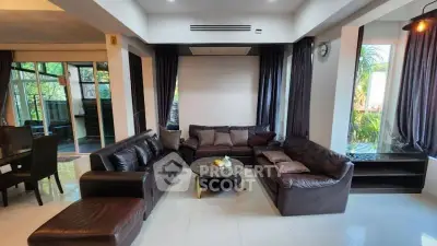 Luxurious living room with elegant leather sofas and large windows offering garden views.