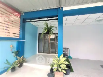 Modern exterior with vibrant blue walls and lush potted plants, perfect for a welcoming entrance.