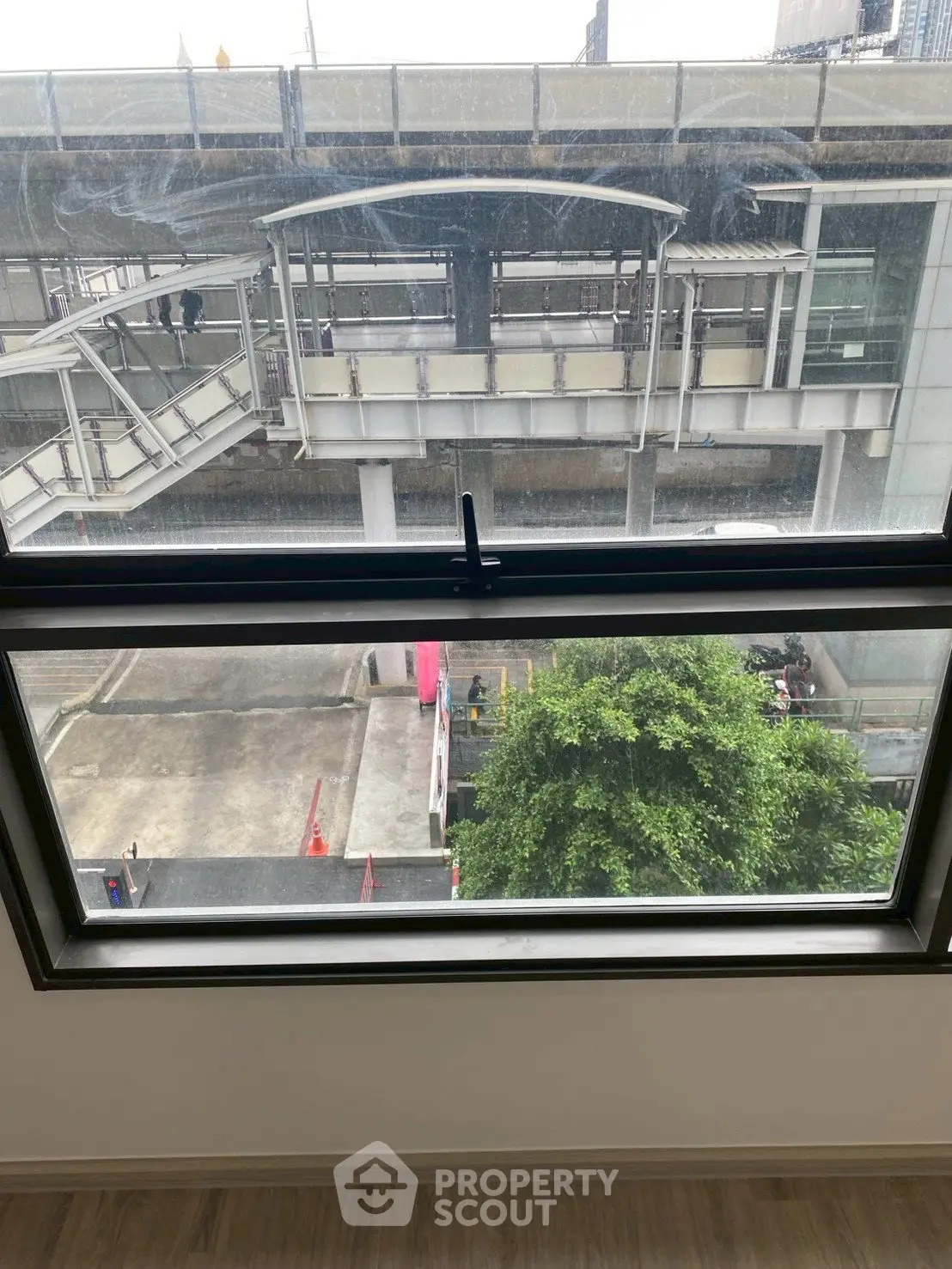 Urban view from a modern apartment window overlooking a city transit station.