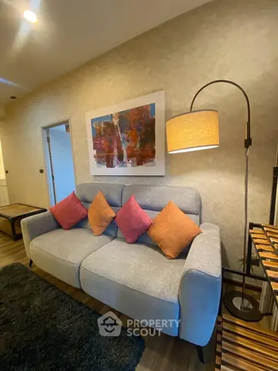 Cozy living room with stylish sofa, vibrant cushions, and elegant floor lamp, perfect for relaxation.