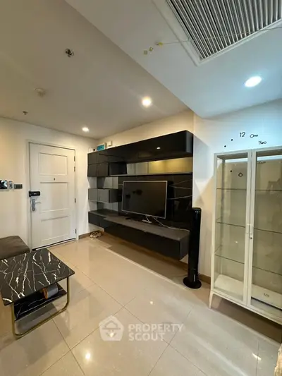 Modern living room with sleek black entertainment unit and glass display cabinet.