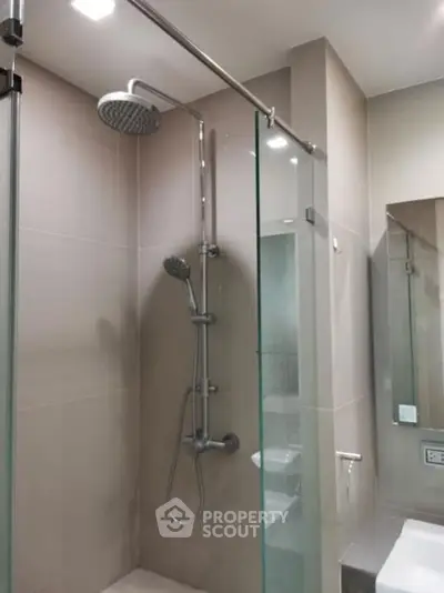 Modern bathroom with sleek shower and glass partition in contemporary apartment.