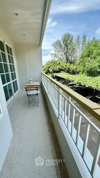 Spacious balcony with scenic view of lush greenery, perfect for relaxation and outdoor dining.