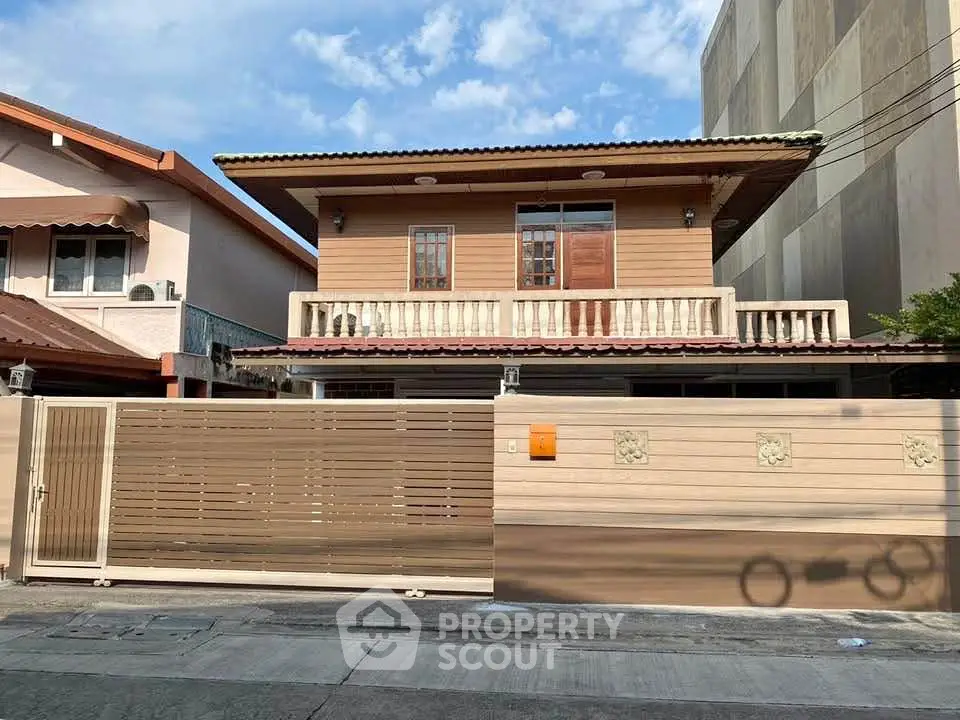 Charming two-story house with modern facade and gated entrance in a serene neighborhood.