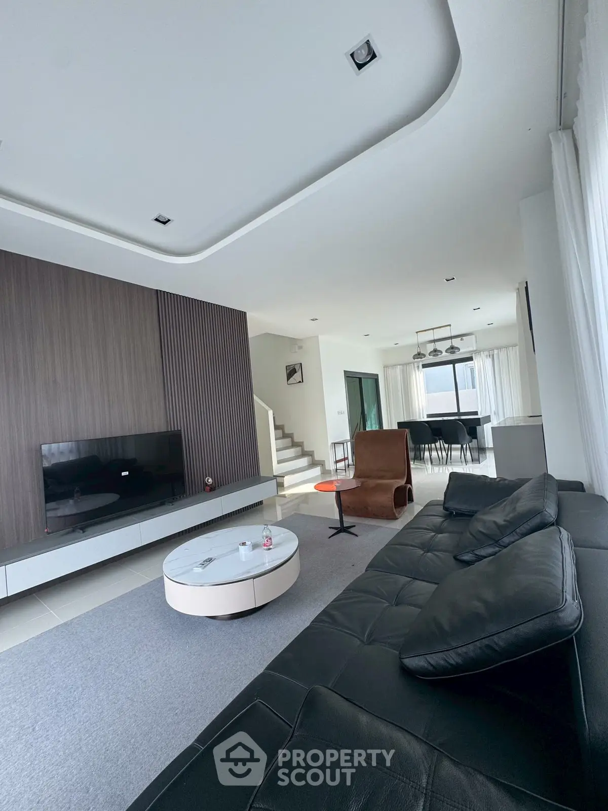 Modern living room with sleek design and open layout, featuring a large black leather sofa and stylish decor.