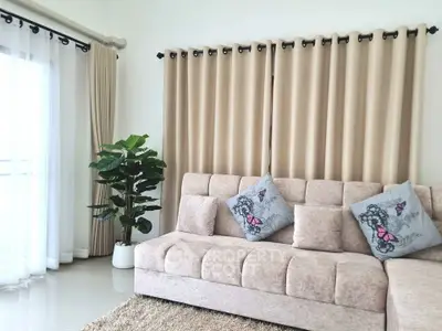 Stylish living room with plush sofa, elegant curtains, and indoor plant for a cozy ambiance.