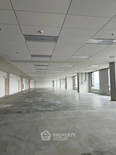 Spacious open-plan commercial space with large windows and modern ceiling lights.