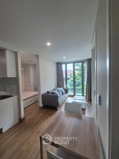 Modern apartment interior with open layout, featuring a cozy living area and large windows with garden view.