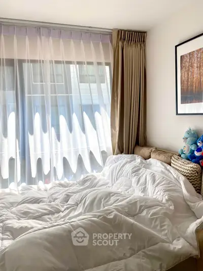 Cozy bedroom with large window and elegant curtains, perfect for relaxation.