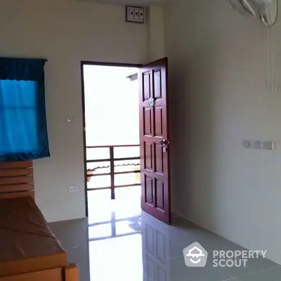 Bright and airy bedroom with glossy tiled flooring, a large window allowing natural light, and an air conditioning unit for comfort.