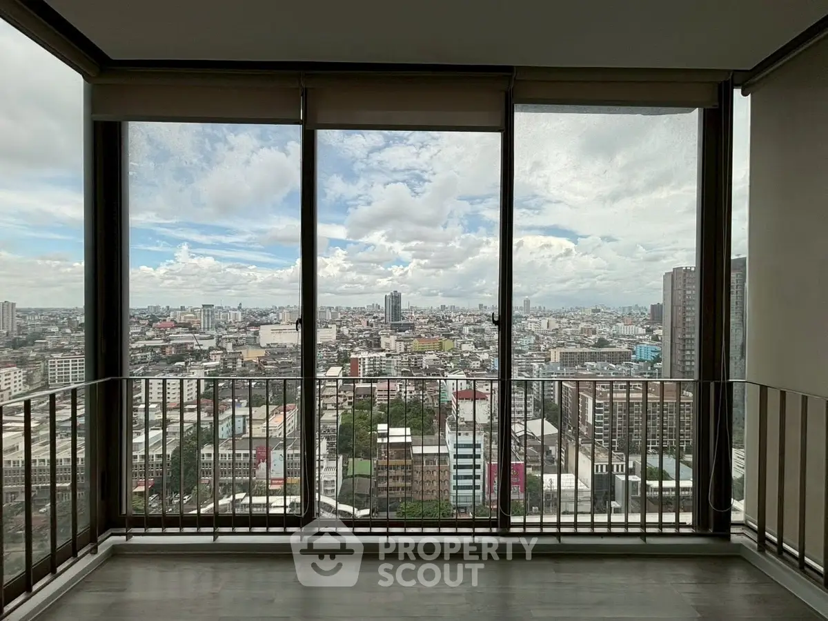 Stunning cityscape view from high-rise apartment with floor-to-ceiling windows and balcony.