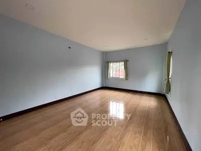 Spacious empty room with wooden flooring and natural light, perfect for customization.