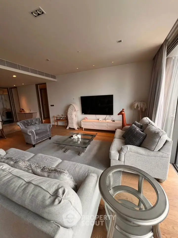 Spacious modern living room with elegant furniture and large TV, perfect for relaxation.