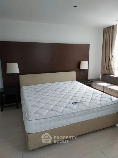 Spacious bedroom with modern decor and large bed in a well-lit room.