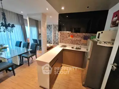 Modern open-layout kitchen with dining area, featuring sleek cabinetry and stylish lighting.