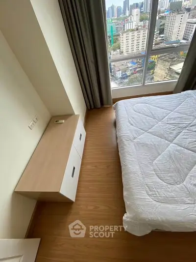 Modern bedroom with city view, featuring sleek wooden flooring and large windows for natural light.