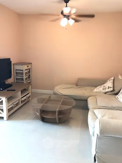 Cozy living room with modern furniture and ceiling fan, perfect for relaxation.
