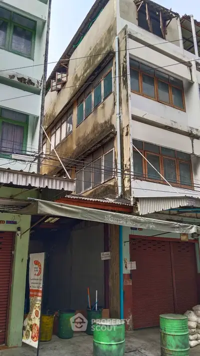 Aged multi-story building with closed shops and weathered facade, ideal for renovation or investment opportunity.