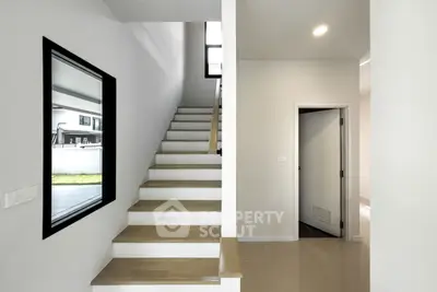 Modern interior with sleek staircase and neutral tones, showcasing contemporary design and spacious layout.
