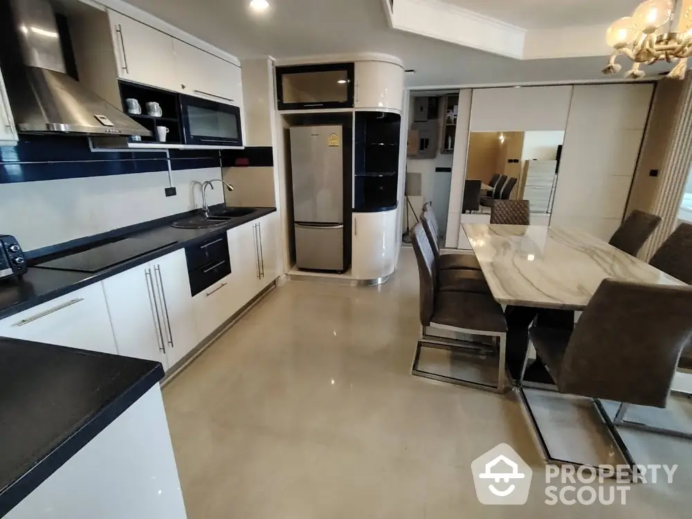 Modern kitchen with sleek design, featuring dining area and stainless steel appliances.