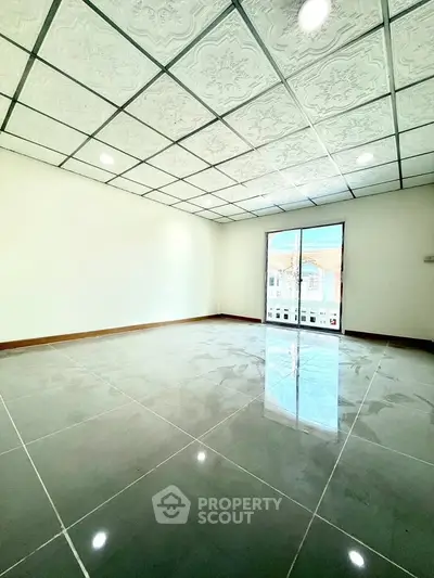 Spacious empty room with glossy tiled floor and decorative ceiling