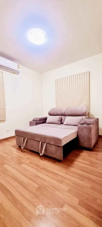 Spacious living room with modern sofa and wooden flooring, perfect for relaxation and comfort.