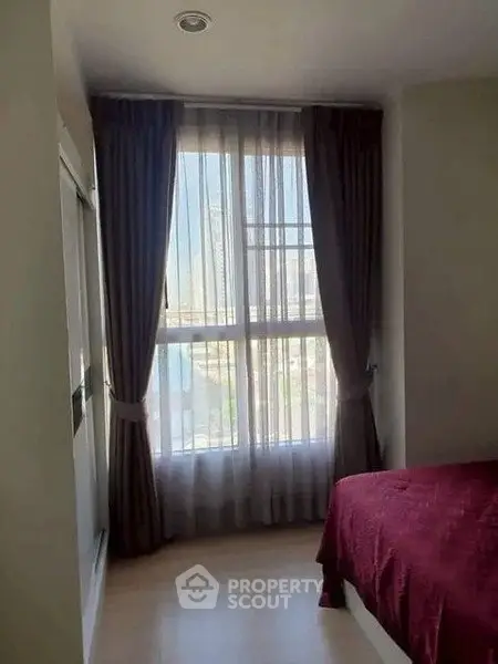 Cozy bedroom with large window and elegant curtains offering natural light and a serene view.