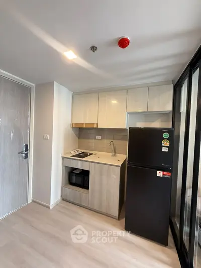 Modern compact kitchen with sleek appliances and stylish cabinetry in a contemporary apartment.