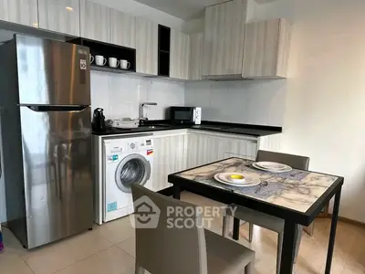 Modern kitchen with sleek appliances and dining area in stylish apartment.