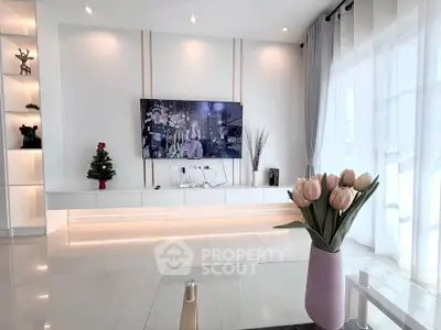 Modern living room with sleek decor and large TV, featuring elegant lighting and stylish furnishings.