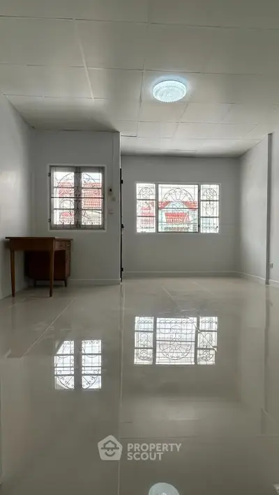 Spacious empty room with glossy tiled floor and large windows, perfect for customization.