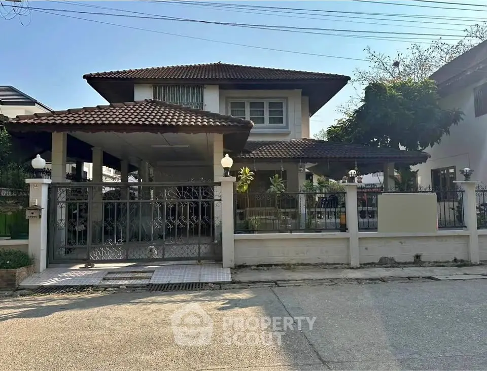 Charming two-story house with tiled roof and gated entrance in a serene neighborhood.