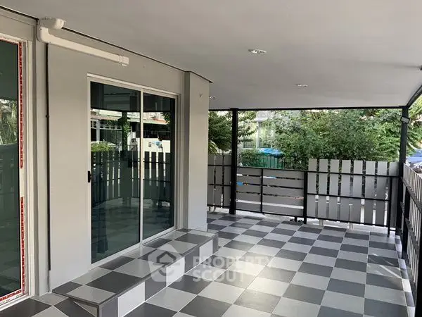 Spacious covered balcony with modern checkered flooring and sliding glass doors.