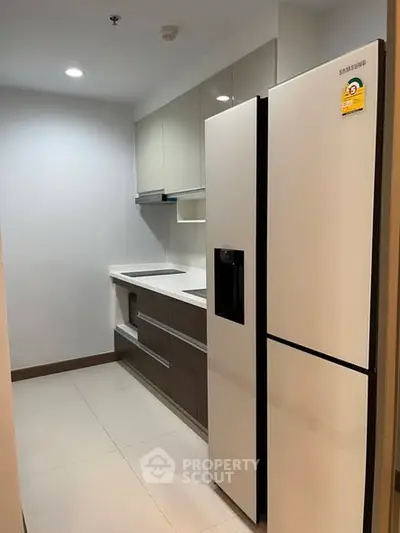 Modern kitchen with sleek cabinetry and large refrigerator in a compact layout.