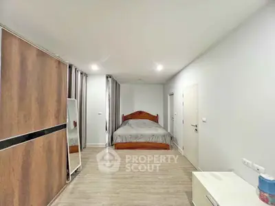 Spacious bedroom with modern decor and wooden flooring, featuring a large bed and ample storage.