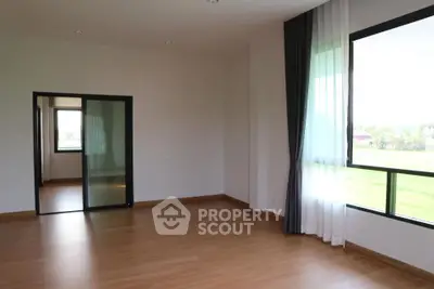Spacious empty room with large windows and wooden flooring, perfect for customization.