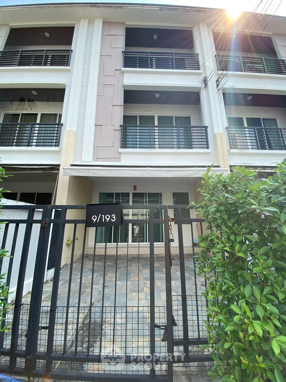 Modern townhouse exterior with gated entrance and sunlit facade, ideal for urban living.