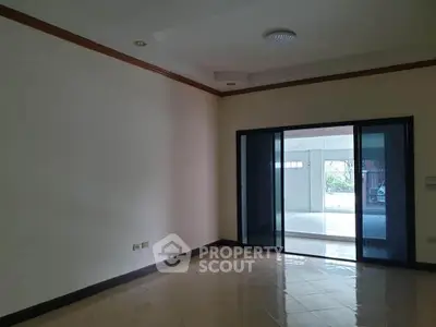 Spacious empty room with sliding glass doors leading to a bright area, ideal for customization.