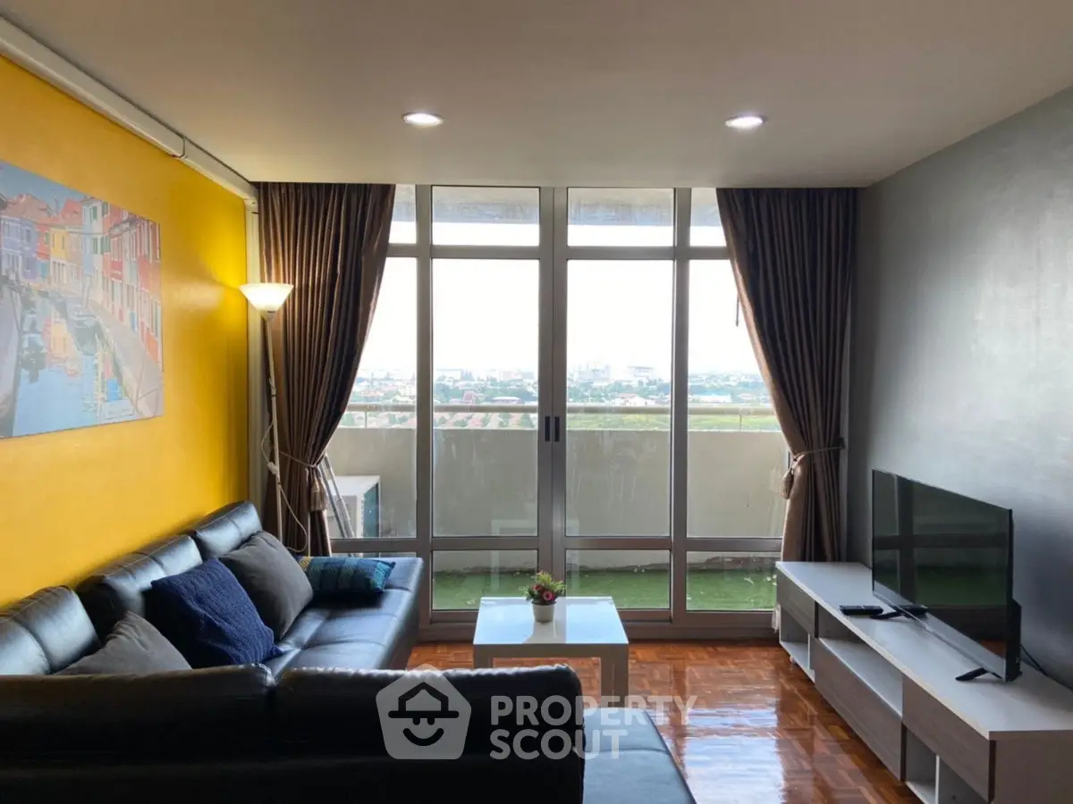Spacious living room with large windows and stunning city view, featuring modern furniture and vibrant decor.