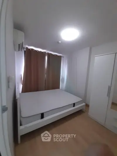 Cozy bedroom with natural light, featuring a bed and wardrobe, ideal for restful living.