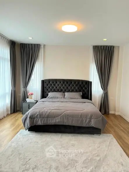 Luxurious bedroom with elegant gray decor and large windows for natural light.