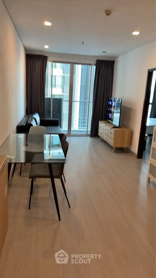 Modern living room with glass dining table and balcony view in a stylish apartment.