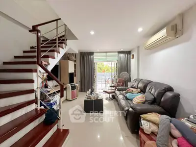 Spacious living room with modern staircase and cozy seating area, perfect for family gatherings.