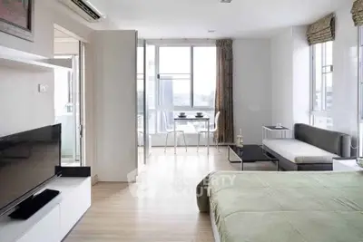 Modern studio apartment with open layout, featuring a cozy living area and dining space with city views.
